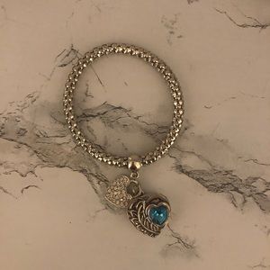 Silver charm bracelet with three charms.